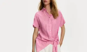 Aesthetic girl w różowej, pasiastym topie z wiązaniem w pasie i białych spodniach.
