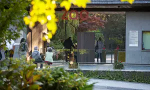 Wejście do największego zoo w Polsce. Ludzie wchodzą przez bramki, a nad nimi wisi napis "ZOO".