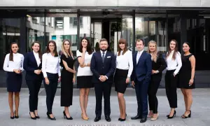 Grupa prawników w eleganckich strojach stoi przed nowoczesnym budynkiem.
