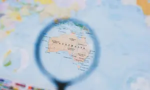 Mapa świata z lupą powiększającą Australię. Planowanie, kiedy są wakacje w Australii, to świetny pomysł na podróż!