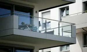Nowoczesna loggia z przeszkloną balustradą, na której stoi stolik z krzesłami.