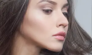 Delikatny profil kobiety z błyszczącymi, różowymi, wąskimi ustami i rozwianymi włosami.