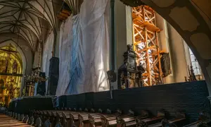 Wnętrze kościoła św. Mikołaja w Gdańsku podczas renowacji. Widoczne ławki, rusztowania i białe płachty zakrywające część zabytkowego wyposażenia.