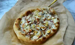 Pyszna pizza bianca z jabłkami i serem, podana na papierze do pieczenia.