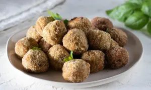Un piatto colmo di polpette di melanzane, dorate e croccanti, pronte per essere gustate. La ricetta originale che conquista tutti.