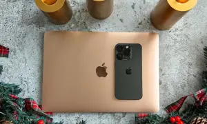 Złoty MacBook i czarny iPhone na tle świątecznych dekoracji. Idealny zestaw do pracy i rozrywki z macOS.