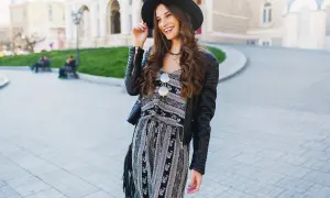Uśmiechnięta dziewczyna w kapeluszu i skórzanej kurtce, prezentująca styl glamour ubrania.