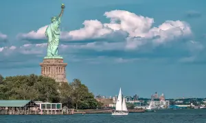 Statua Wolności i żaglówka na wodzie. Zastanawiasz się, ile kosztuje lot do USA z Polski?