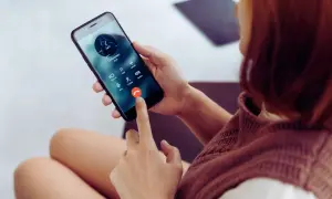 Kobieta trzyma telefon, na ekranie połączenie od nieznanego numeru. Zastanawiasz się, jak sprawdzić, czy telefon jest na podsłuchu?