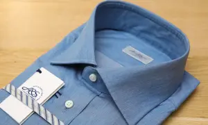 Camicia azzurra con colletto button down, etichetta e nastro a righe.