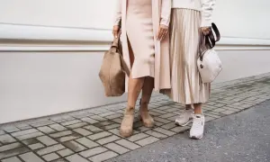 Dwie kobiety w beżowych sukienkach i kardiganach, jedna w zamszowych botkach, druga w sneakersach. Stylowe buty do beżowej sukienki.