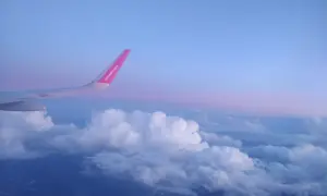 Skrzydło samolotu Wizz Air nad chmurami, wczesny poranek. Czas na loty do Anglii!