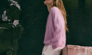 Kaszmirowy sweter w kolorze pudrowego różu otula ciało, dowodząc, czy kaszmir jest ciepły. Modelka w beżowych spodniach.