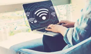 Osoba pracuje na laptopie, na ekranie widoczne są ikony Wi-Fi i schematy. Dowiedz się, jak włączyć Wi-Fi w laptopie.