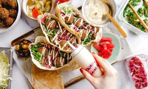 Leckeres Falafel-Rezept: Pita gefüllt mit Falafel, Salat, roten Zwiebeln und Tahini-Sauce. Dazu Hummus, Oliven und eingelegtes Gemüse.