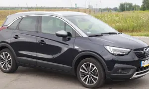 Ciemnogranatowy Opel Crossland z dwukolorowym dachem, stojący na tle łąki. Wady i zalety tego modelu to temat dyskusji.