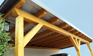 Holzkonstruktion eines Carports mit Trapezblechdach. Das Dach ist gut abgedichtet und schützt das darunter geparkte Auto.
