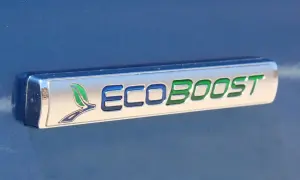Ford Focus 1.0 EcoBoost kamremsbyte pris. Ett emblem på en blå bil visar "ECOBOOST" med gröna och blå bokstäver.