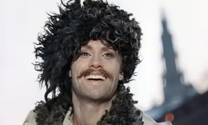 Daniel Olbrychski w filmach, z charakterystyczną burzą loków i wąsami, uśmiecha się szeroko.