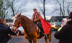 Chłopiec w stroju św. Marcina, na kasztanowym koniu, z czerwoną peleryną. To część tradycji bractwa konnego św. Marcina.