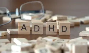 Drewniane klocki z literami "ADHD" i rozrzucone po stole, sugerujące poszukiwanie rozwiązań, np. leki na ADHD.