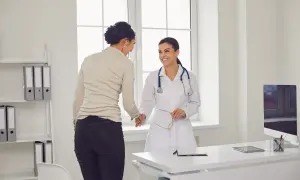 Uśmiechnięta lekarka w białym kitlu wita pacjentkę. To udana wizyta u psychiatry, pełna nadziei na poprawę.