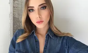 Młoda kobieta w dżinsowej koszuli, z makijażem i blond włosami, przypomina córkę Eminema.
