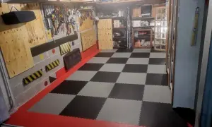 Pavimento a scacchi in piastrelle carrabili per garage, con bordi rossi e pareti attrezzate per gli attrezzi.