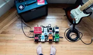 Gitarzysta przygotowuje się do sesji, jego stopa blisko pedałów efektowych. Wzmacniacz Fender i gitara elektryczna czekają na dźwięk.