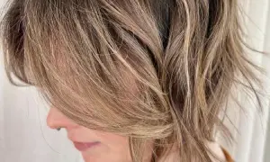 Kobieta z brązowymi, rozjaśnianymi pasmami i lekko potarganymi, shaggy hair.