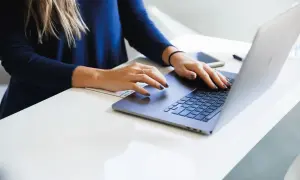 Mani di donna su tastiera laptop, analizzando il costo aziendale.