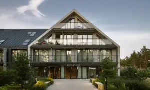 Nowoczesny budynek hotelowy Saltic Resort & Spa Łeba z betonową fasadą i przeszklonymi balkonami.
