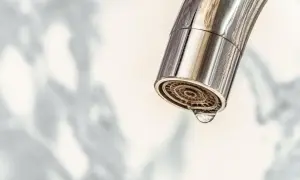 Nahaufnahme eines Chromwasserhahns mit einem Tropfen, der aus dem Sieb fällt. Zeit für das Wasserhahn Sieb reinigen.