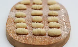 Gnocchis faits maison, une délicieuse pâte italienne à base de pomme de terre, saupoudrés de sucre glace sur une planche en bois.