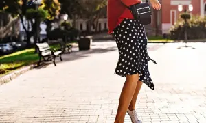 Letnia stylizacja: czarna spódnica w grochy, białe trampki i czerwony kardigan. Idealna na spacer po mieście.
