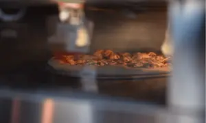 Pizza pieczona w piekarniku, widok z bliska na chrupiący spód.
