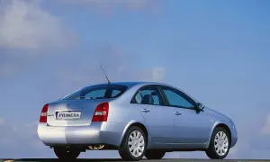 Srebrny Nissan Primera 2002 z widokiem z tyłu, zaparkowany na drodze pod błękitnym niebem.