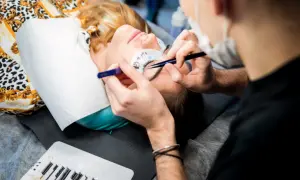 Profesjonalny kurs przedłużania rzęs, gdzie najlepiej? Stylistka precyzyjnie dokłada kępki.