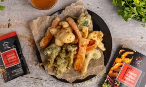 Chrupiące warzywa w tempurze, takie jak brokuły i marchewka, podane na talerzu z sosem. Obok opakowanie mieszanki do tempury.