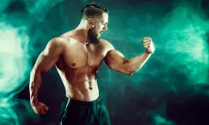 Mięśniowy mężczyzna napina biceps. Czy to efekt kwasu mlekowego?