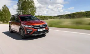 En röd Dacia Jogger begagnad kör på en landsväg i Sverige. Bilen är i rörelse med suddig bakgrund.