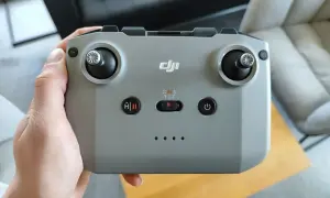 Dłoń trzyma szary kontroler DJI, gotowy do sterowania dronem.