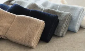 Gestapelte Mützen in Beige, Dunkelblau, Grau und Hellblau. So pflegt man Kaschmir, damit er lange schön bleibt.