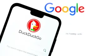 Telefon z DuckDuckGo, jedną z wyszukiwarek internetowych, obok rozmazanego logo Google.