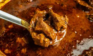 Ein Löffel voller herzhaftem Wildschwein Gulasch, das in einer reichen, dunklen Sauce schmort.