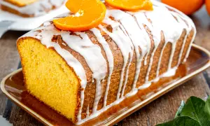 Omas saftiger Orangenkuchen, mit Zuckerguss und frischen Orangenscheiben garniert, duftet herrlich auf dem rustikalen Holztisch.