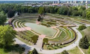 Widok z lotu ptaka na park Cytadela z jeziorem, tarasami i alejkami. W tle zabudowania miejskie.