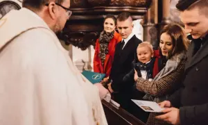 Rodzina świętuje, kiedy chrzci się dzieci. Ksiądz błogosławi niemowlę trzymane przez matkę, podczas gdy ojciec i chrzestni patrzą z dumą.