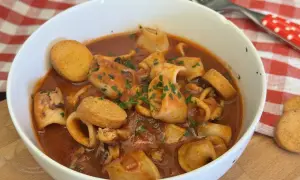 Un invitante piatto di moscardini in umido, ricchi di sapore e guarniti con prezzemolo fresco, accompagnati da crostini dorati.