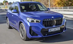 Niebieskie x1 bmw z kierowcą w okularach przeciwsłonecznych jedzie po drodze.